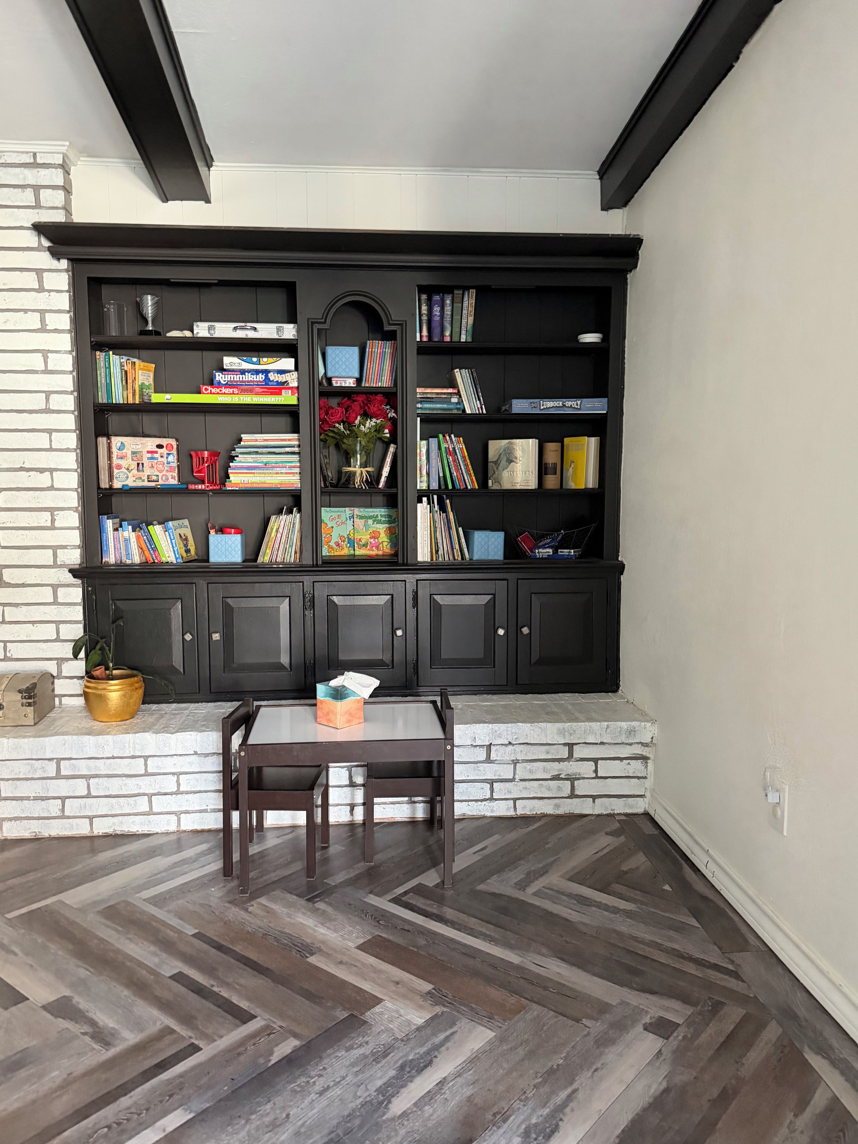 A room with a built-in bookshelf, a table, and a chair.