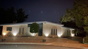 A brick building with a flat roof, large windows, and a small tree in front. - Our Pool House (Lubbock)