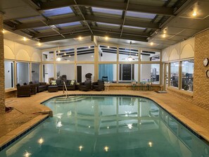 Ein Innenpool mit Korbmöbeln, großen Fenstern und einer Decke mit Dachfenstern.