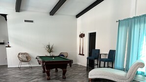 A room with a pool table, a sofa, and a dining area. - Our Pool House (Lubbock)