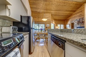 A modern kitchen with granite countertops, stainless steel appliances, and a wooden ceiling. - Telemark 8 - Ski in Walk out, Private Sauna, Short Walk to the Village (Whistler)