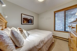 A bedroom with a bed, a window with blinds, a dresser, and a framed picture on the wall. - Telemark 8 - Ski in Walk out, Private Sauna, Short Walk to the Village (Whistler)