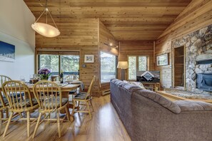 A cozy cabin interior with a dining area, a sofa, a fireplace, and a stone wall. - Telemark 8 - Ski in Walk out, Private Sauna, Short Walk to the Village (Whistler)