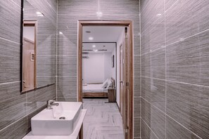 A modern bathroom with a large sink, a mirror, and a wooden door leading to a bedroom. - MINT HOTEL (Ho Chi Minh City)