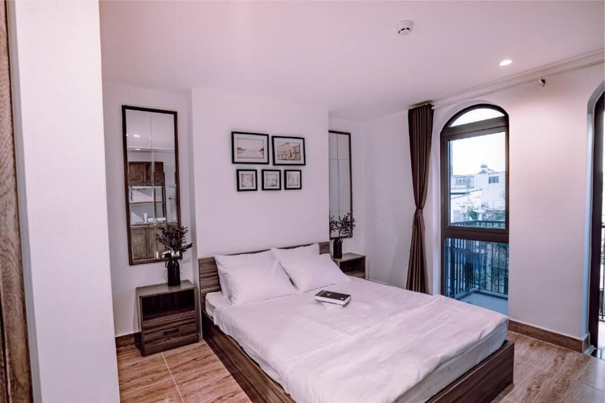 Un dormitorio moderno con una cama grande, una mesita de noche, un espejo y una ventana con cortinas.