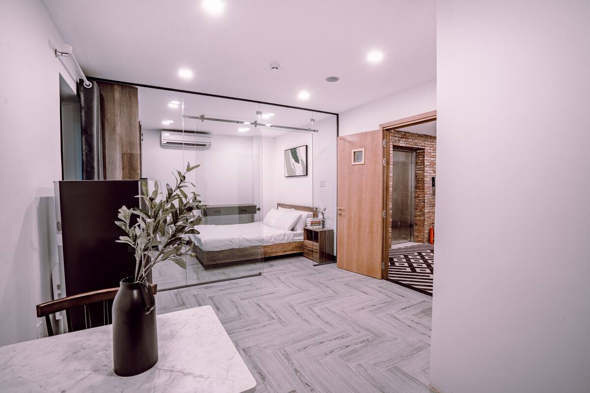 Un dormitorio moderno con una cama, una mesita de noche y un florero con flores.