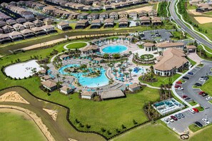 A residential area with a central swimming pool, multiple buildings, and a parking lot.