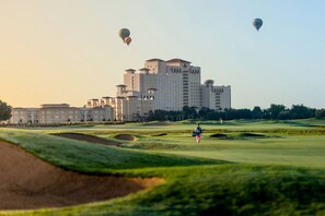 A golf course with a large hotel building in the background.