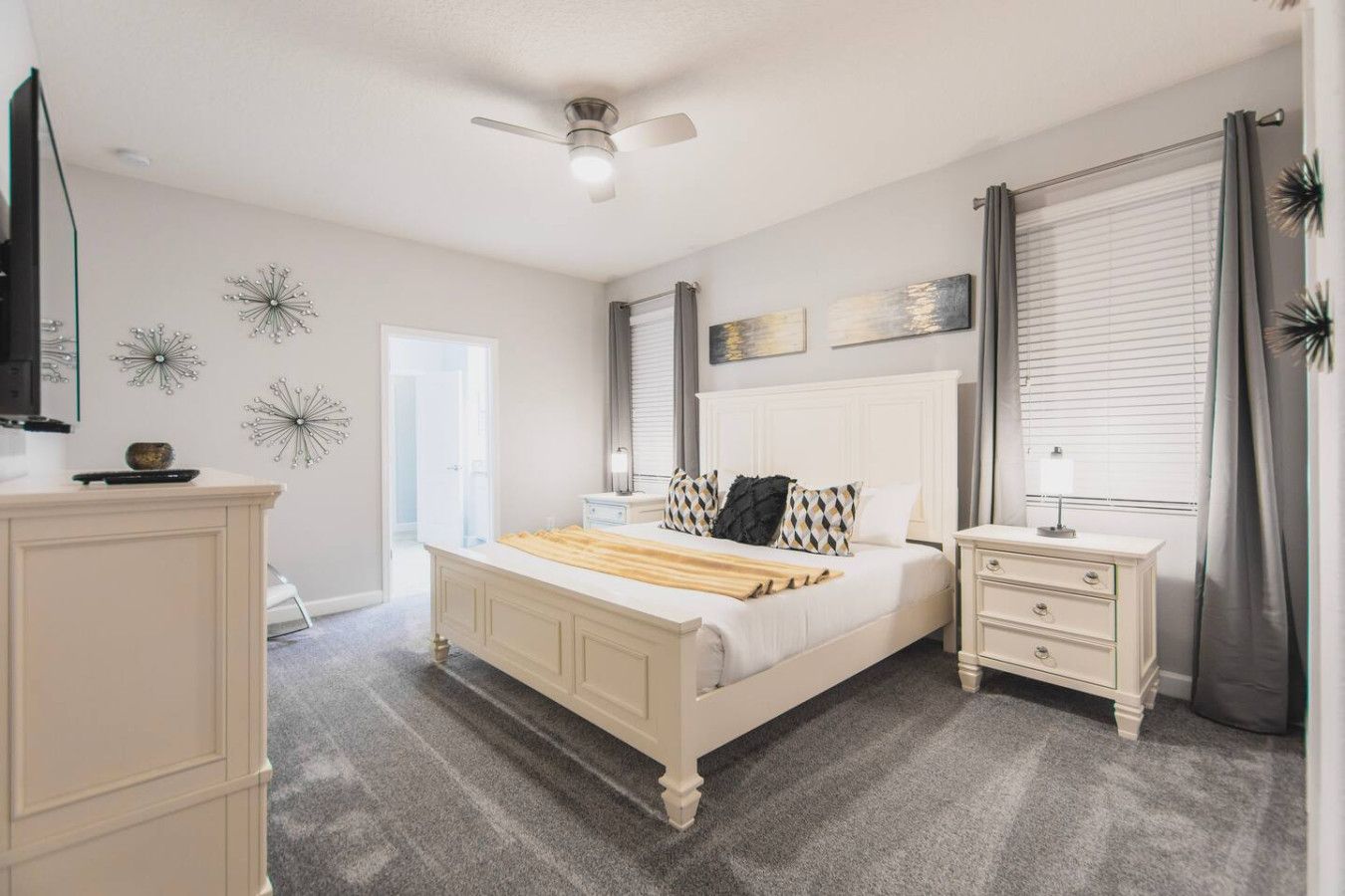 A bedroom with a bed, bedside tables, a ceiling fan, and decorative wall art.