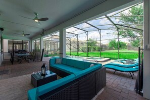 A covered patio with a pool, outdoor furniture, and a view of a backyard.