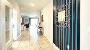 A hallway with a clear floor, a decorative wall panel, and a door leading to another room.