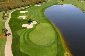 A golf course with a pond, sand bunkers, and a walking path.