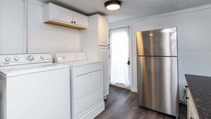 A compact kitchen with a stainless steel refrigerator, a washing machine, and a dryer. - Little Lansing House I 3 BR w/ Queen beds (Lansing)