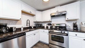 A modern kitchen with white cabinets, stainless steel appliances, and a granite countertop. - Little Lansing House I 3 BR w/ Queen beds (Lansing)