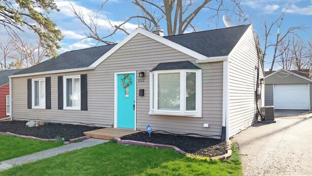 A single-story house with a front door, a garage, and a small front yard. - Little Lansing House I 3 BR w/ Queen beds (Lansing)