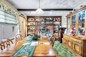 A dining area with a wooden table, chairs, and a brick fireplace. - Country suite - Red Barn village (Clarks Summit)