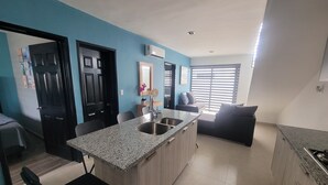 Una cocina moderna con encimeras de granito, un lavamanos y un comedor con sillas.