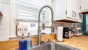 A kitchen with a modern stainless steel sink, a curved faucet, and a window with blinds. - Simple & Sweet 2 BR 1 BA Home in Lansing - Cynwood (Lansing)