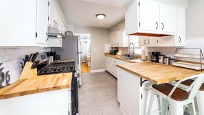 A modern kitchen with white cabinets, a wooden countertop, and a stove. - Simple & Sweet 2 BR 1 BA Home in Lansing - Cynwood (Lansing)