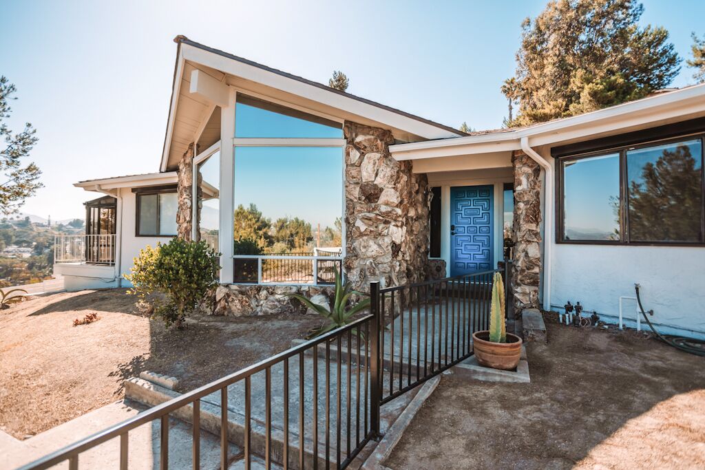 A modern house with a stone facade, large windows, and a blue door.