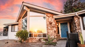 Una casa moderna con fachada de piedra, ventanas grandes y una puerta azul.