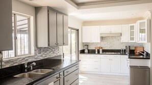 Una cocina moderna con armarios blancos, encimera negra y pileta de acero inoxidable.