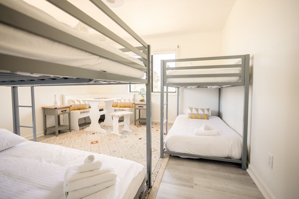 A dormitory room with bunk beds, a desk, and a chair.