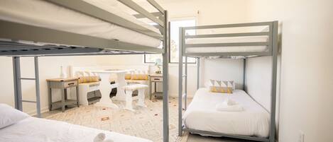 A dormitory room with bunk beds, a desk, and a chair.