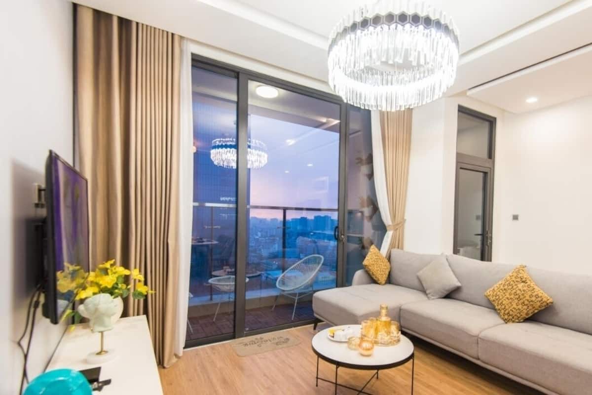 A modern living room with a grey sofa, a round coffee table, and a chandelier.