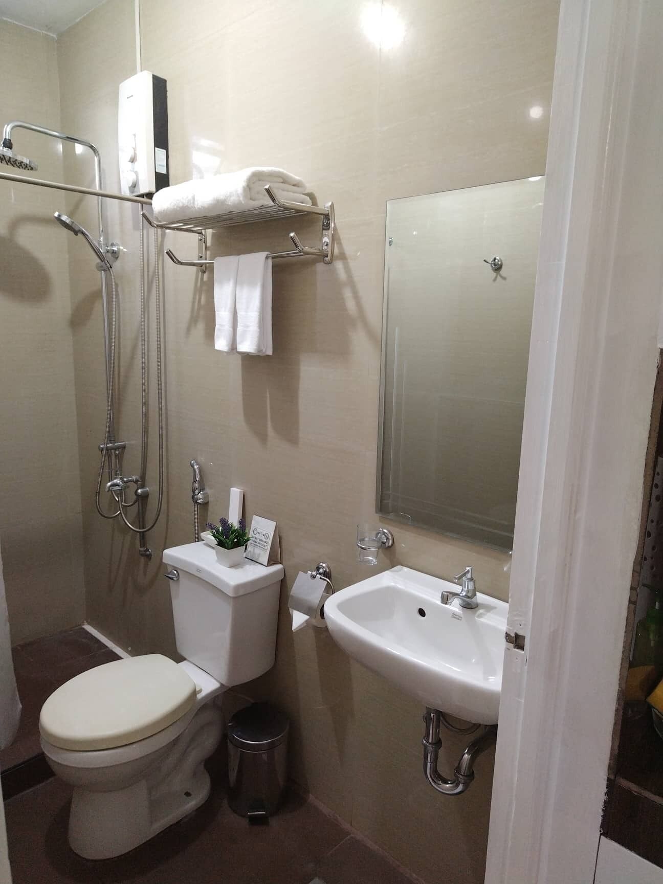 A bathroom with a toilet, bidet, sink, and a towel rack.