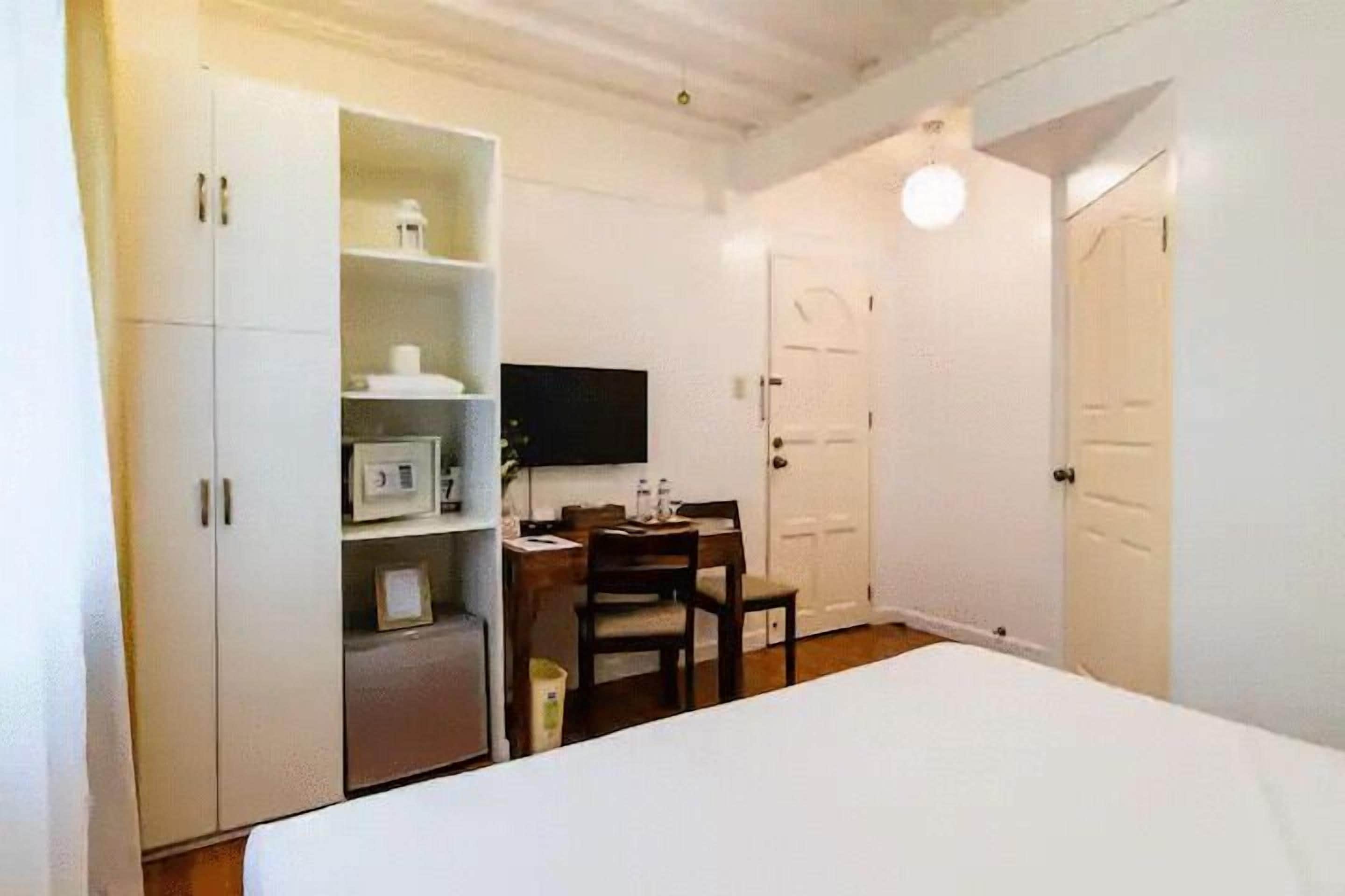 A bedroom with a bed, a desk with a chair, a television, and a wardrobe.