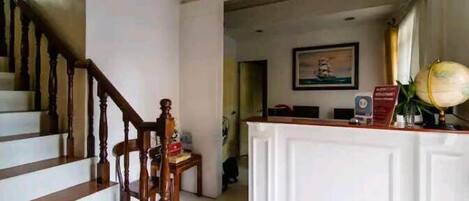 A reception area with a wooden staircase, a reception desk, and a framed picture on the wall.