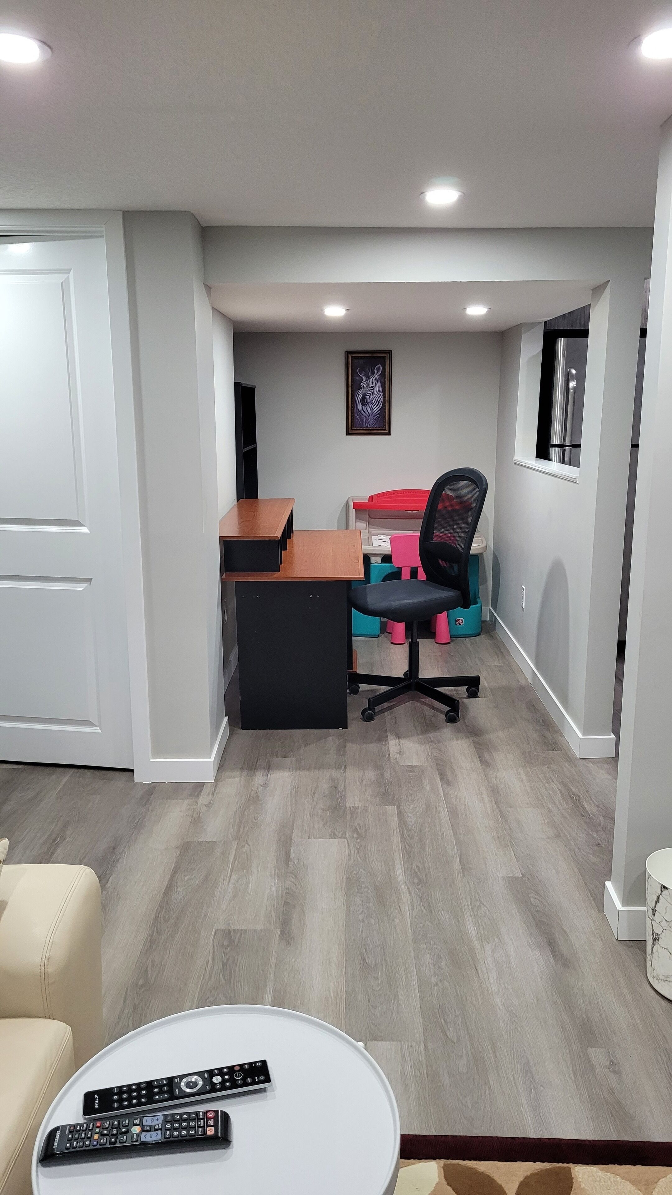 A home office with a desk, office chair, and a framed zebra artwork on the wall.