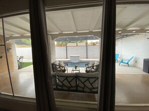 A patio area with a pool, outdoor furniture, and a brick wall.