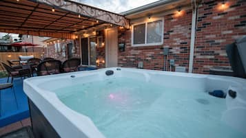 Relax in the hot tub surrounded by a deck and pergola, perfect for unwinding and dining.