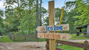 Een houten bord met aanduidingen naar 'Geo Dome' en 'Ranch House' in Texas.