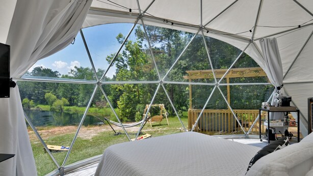 Een ruime tent met een bed, een hangmat en een koffiebar.