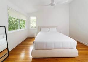 Relax in a serene space with a large bed, ceiling fan, and natural light pouring in through the large window.