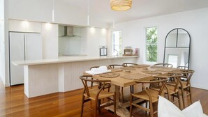 Une cuisine moderne avec des meubles blancs, un îlot central doté de sièges et un luminaire suspendu.