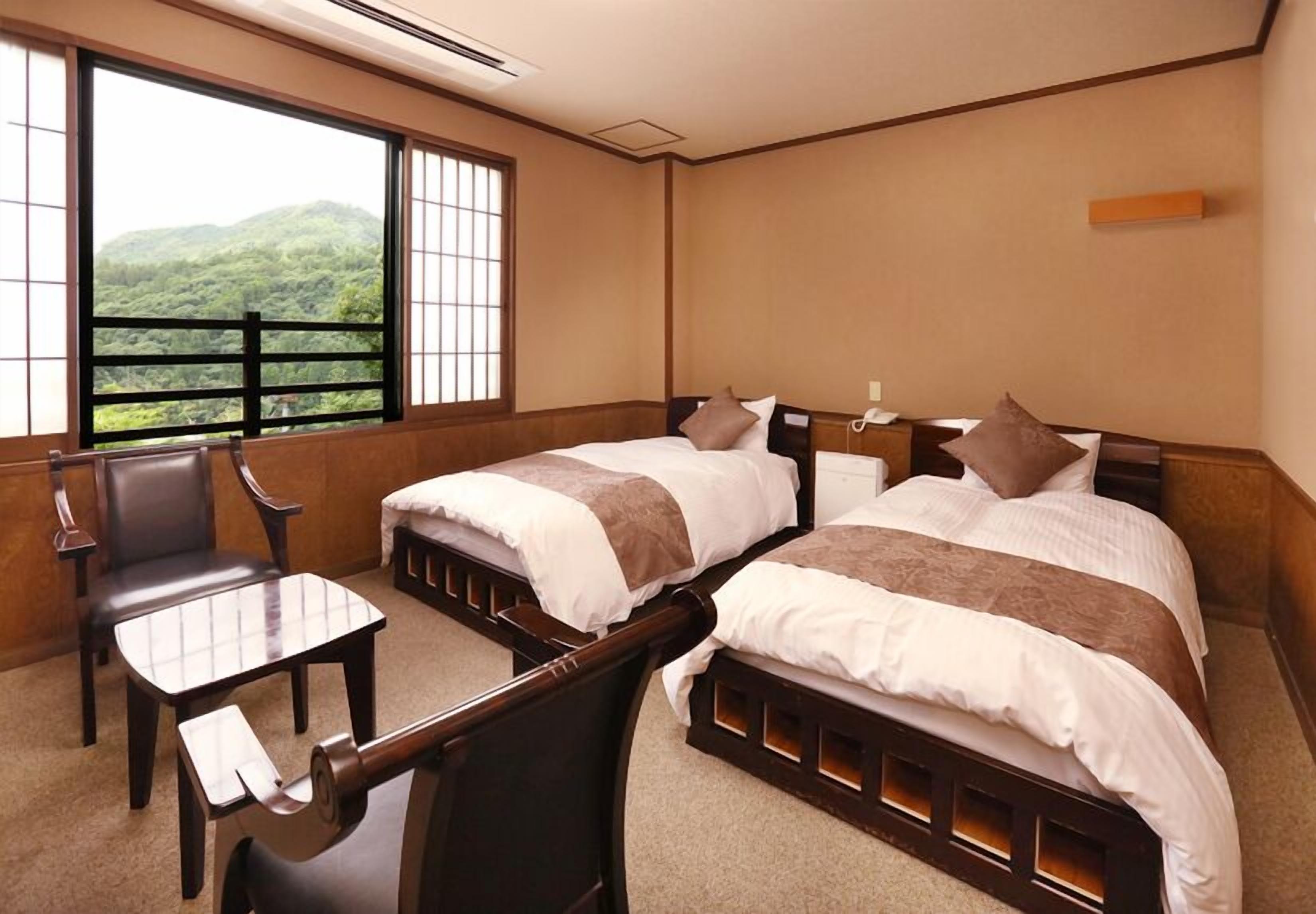 Een hotelkamer met twee bedden, een bureau en een stoel.