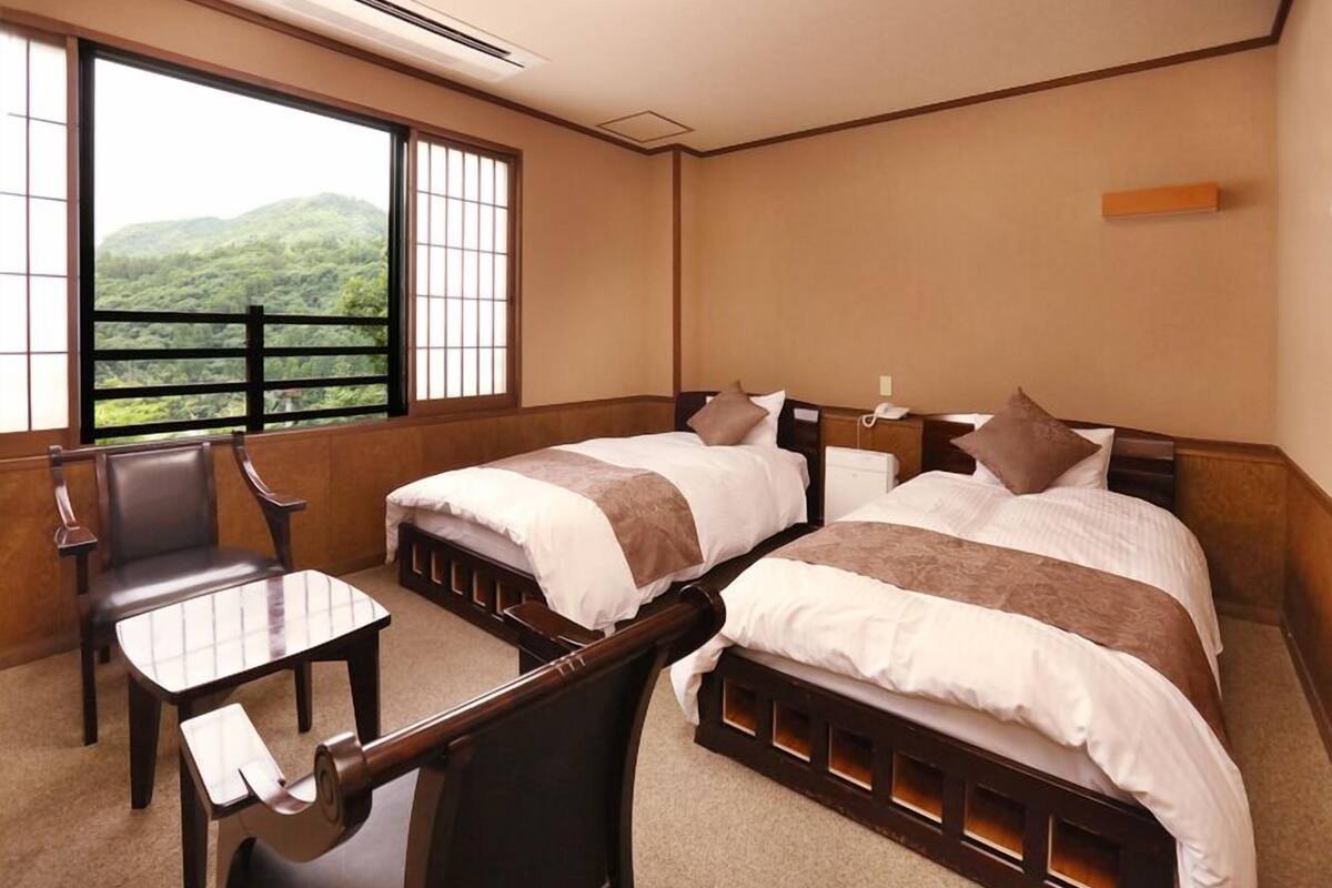 Une chambre d’hôtel avec deux lits, un bureau et une chaise.