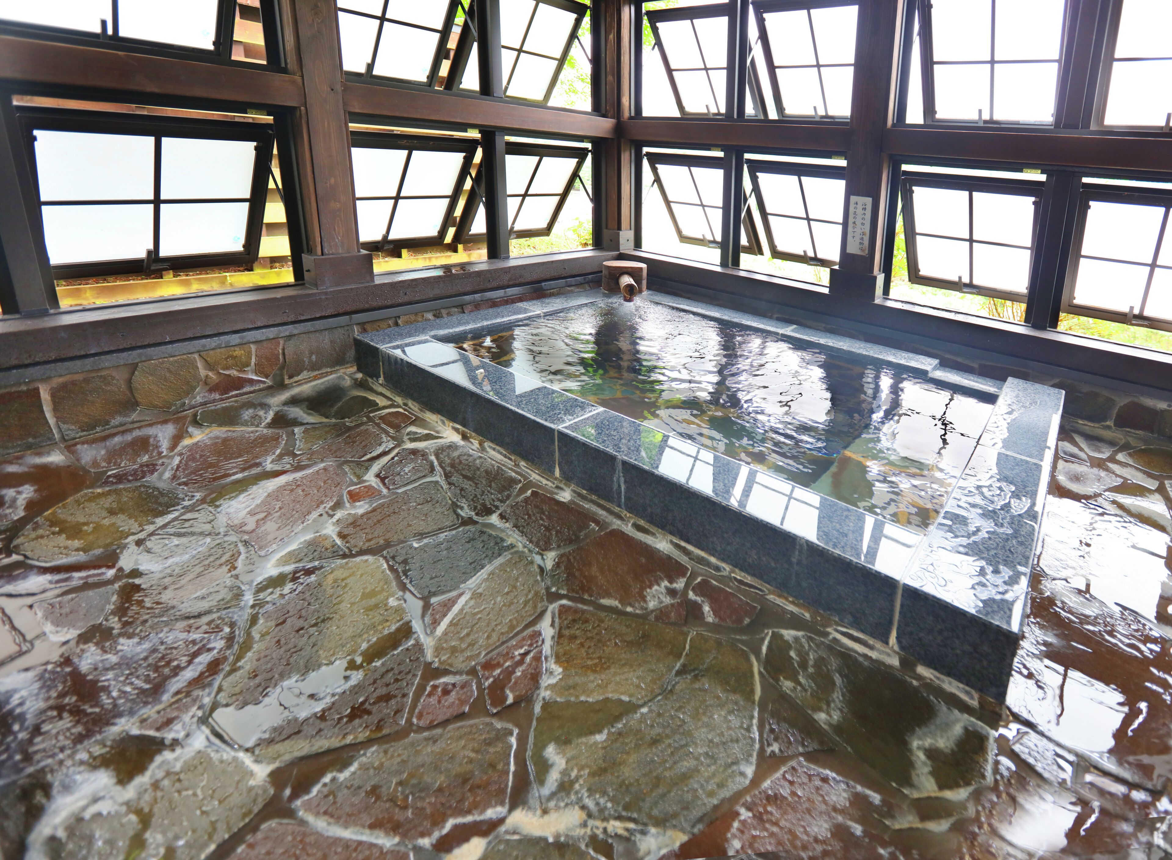 A stone-floored hot tub area with a glass-enclosed window structure.