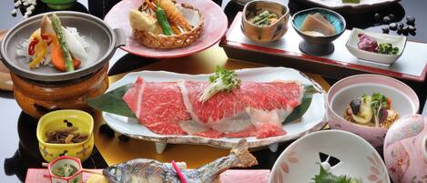 Variedad de platos que incluyen sashimi, pescado y verduras, dispuestos sobre una mesa con varios cuencos y fuentes.