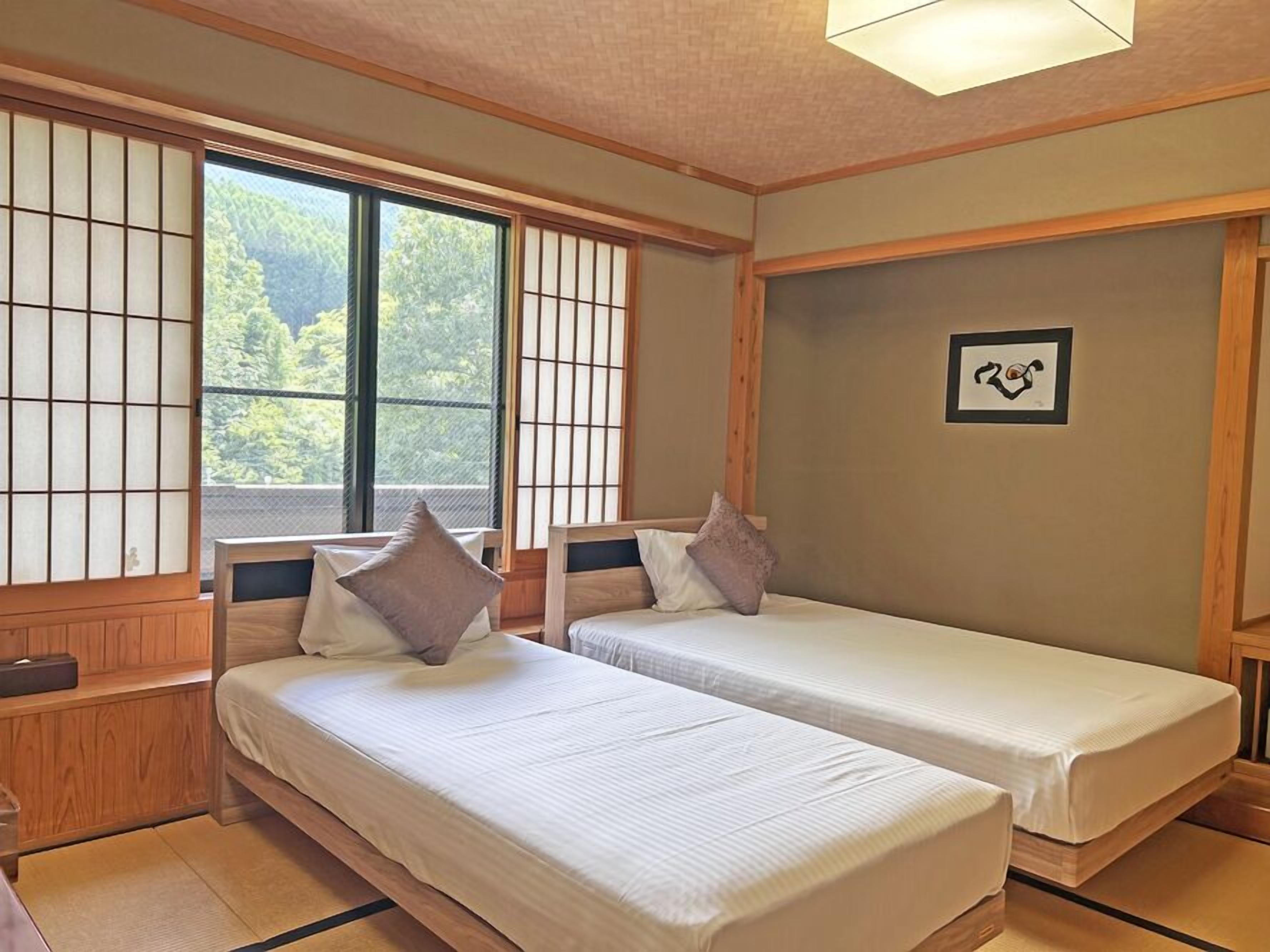 Een traditionele Japanse kamer met twee bedden, tatami vloeren, shoji schermen en een lijst met een foto aan de muur.