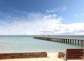 A pier extending into calm waters with a clear sky above.