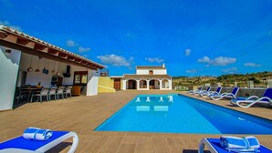A poolside area with lounge chairs and a dining setup. - Rosalia - holiday home with panoramic view and private pool in Teluda (Teulada)
