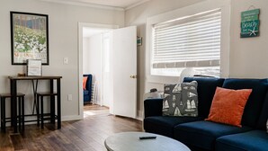 A living room with a blue sofa, a round coffee table, and a framed picture on the wall.