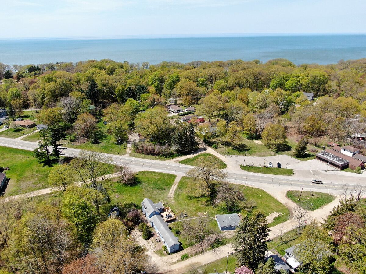 An aerial view of a residential area with houses, roads, and a body of water in the background.