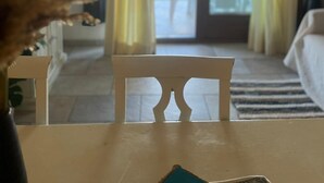 Una habitación con una mesa blanca, una silla y vistas a un espacio exterior con patio y una silla.