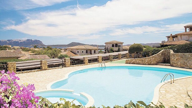 Una piscina con paredes de piedra y vistas a montañas al fondo.
